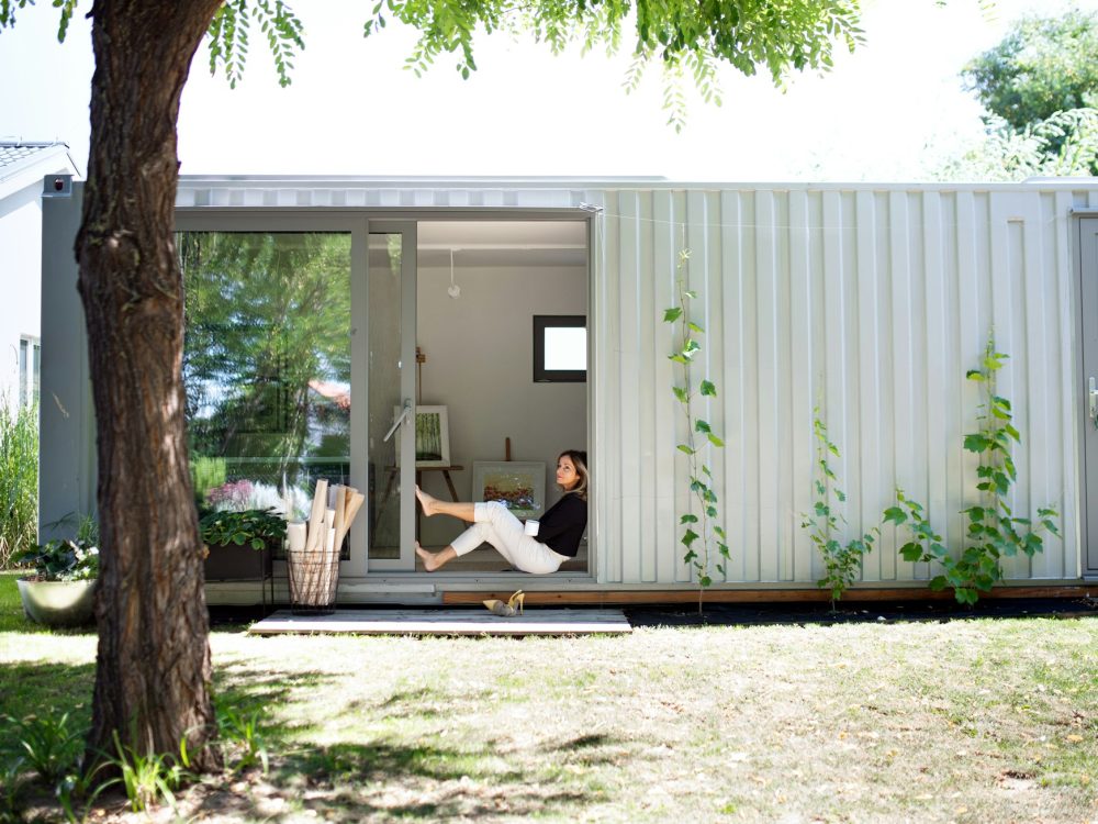 Mature woman working in home office in container house in backyard, resting.